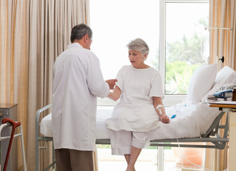 Obraz premium Mature doctor taking the blood pressure of his patient