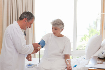 Mature doctor taking the blood pressure of his patient