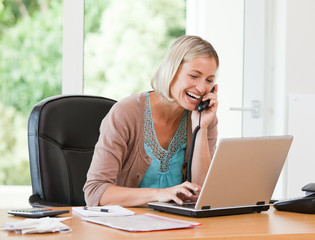 Woman working on her computer while she is phoning