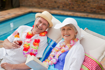 Mature woman reading a book while her husband is drinking a cock