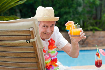 Mature man drinking a cocktail  beside the swimming pool