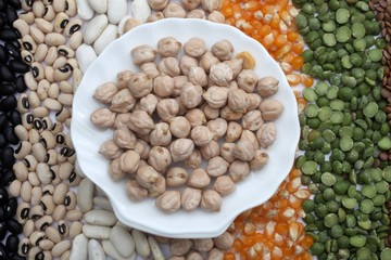 Ceramic plate with chickpeas  over seeds and grains background