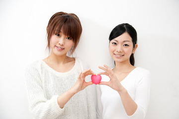two beautiful asian women holding a symbol of heart