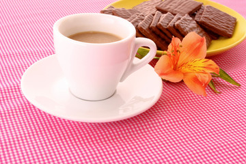 Chocolate cookie and cup of coffee on red background