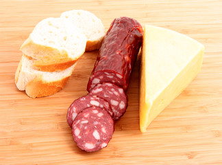 Sausage, bread and cheese on wooden plate
