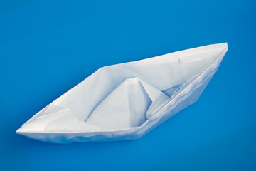 closeup of sinking folded paper ship in blue water