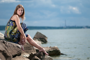 Fototapeta na wymiar sad woman in dress sitting on rock