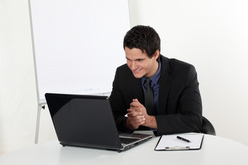 Junger Mann erfolgreich lachend am Laptop