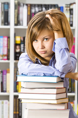 The thoughtful woman sitting with books in the library