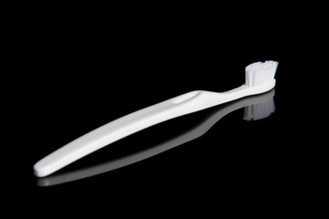 White Toothbrush On Reflective Black Background
