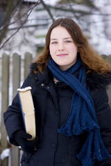 Smiling young girl with book in winter