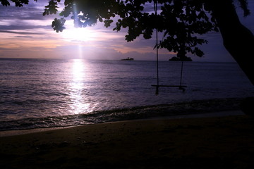 The swing on beach and sunset