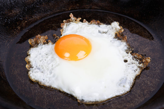 Fried eggs on a frying pan on a board