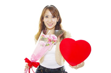 ハート形のプレゼントボックスと花束を持っている笑顔の女性