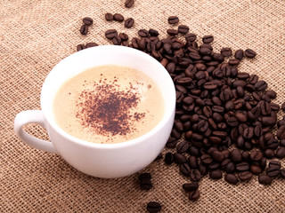 Coffee beans with cup on canvas