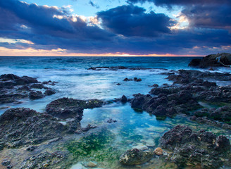 Seashore with reflections in water during sundown.