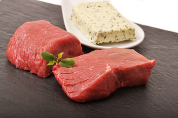 Rohe Steaks und Teller mit Kräuterbutter