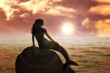 Foto auf Glas Eine Meerjungfrau, die bei Sonnenuntergang auf dem Felsen sitzt © rudall30