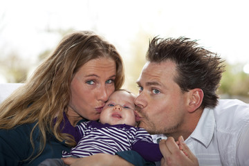 stolze Eltern küssen ihre Tochter