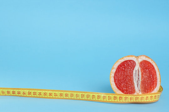 Cut half of juicy grapefruit with centimeter on blue background