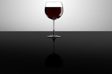 Red wine glass on black reflective surface