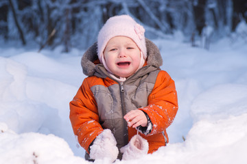 Fototapeta na wymiar Adorable baby disappointed after eat cold snow in winter forest.