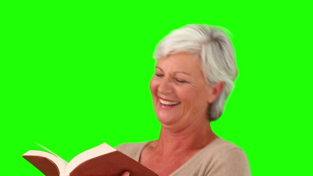 Senior woman smiling while reading a book