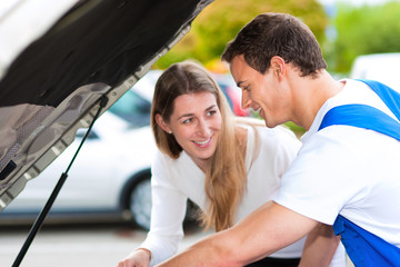 Frau spricht mit Automechaniker in Werkstatt