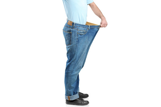 Male showing his lost weight by putting on jeans