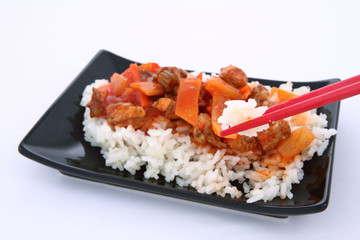 Chinese food-sweet and sour chicken-being eaten with chopsticks