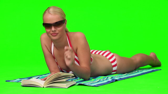Woman in swimsuit with sunglasses reading a book