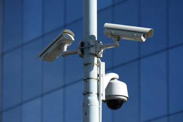 three security cameras on front of glass building