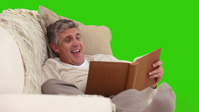 Senior man laughing while he is reading a book