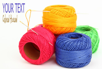 Colored thread, needles and buttons on a white background