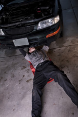 Auto mechanic working under a car repairing an engine