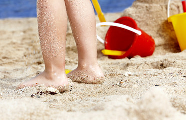Child leg in sand.