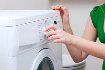 Frau beim Wäsche waschen mit Waschmaschine