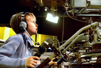 Little boy with headphones and microphone looks to camera