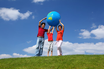 Boy with  mother and father stand on  grass and lift an globe