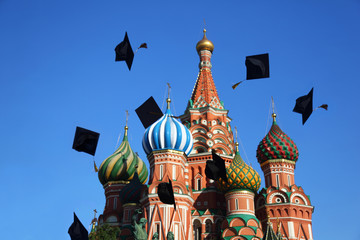 Black hats of graduation throw  in sky near St. Basil Cathedral.