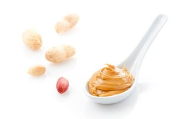 Creamy peanut butter in a white spoon with peanuts