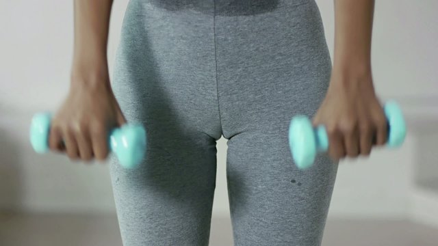 Woman exercising with small weights in gym