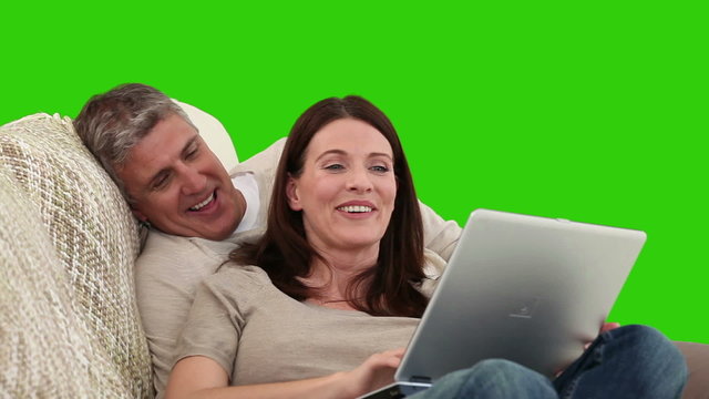 Retired couple using a laptop on their sofa