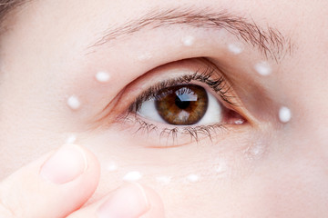 Fototapeta premium Women applying eye skin cream