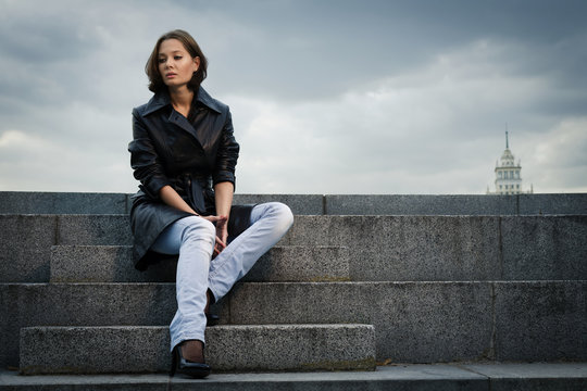 Beautiful young woman sitting on stone steps