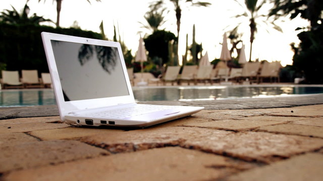 Laptop lying near to swimming pool