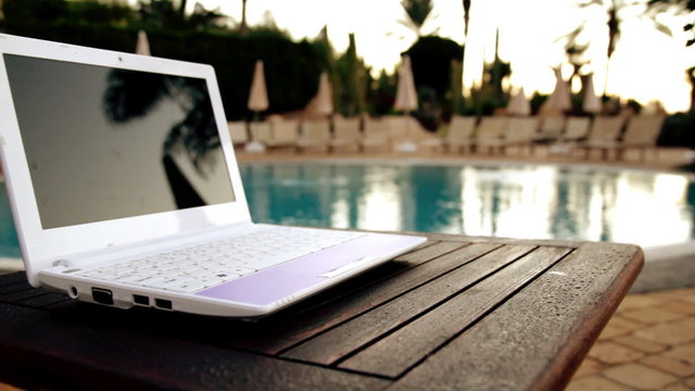 Laptop lying near to swimming pool