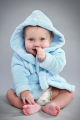 Charming baby in a blue bathrobe