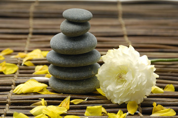 ranunculus flower with petal and stacked stone on mat