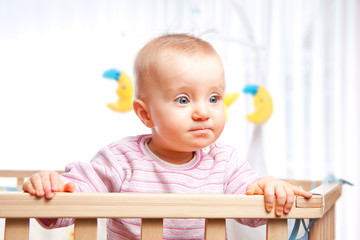 Baby im Laufstall schaut ernst und konzentriert